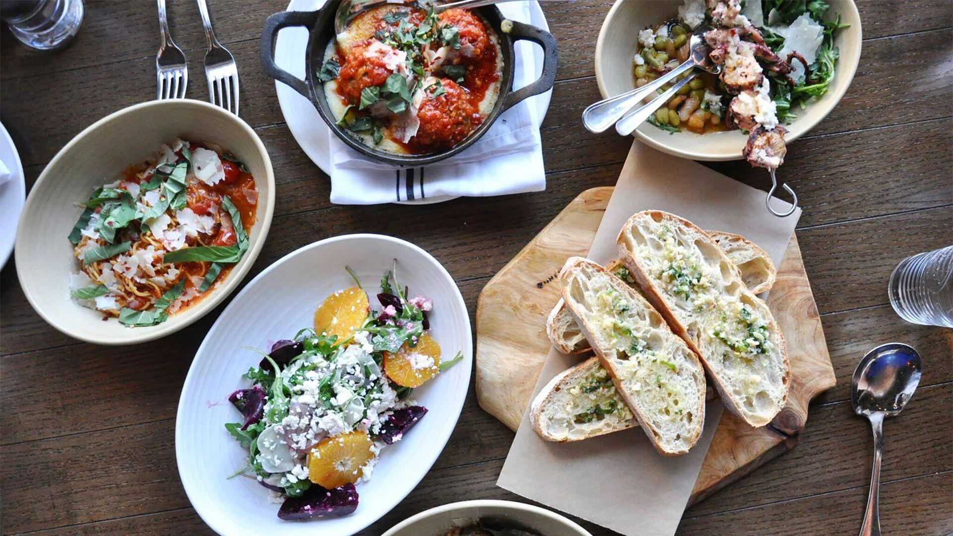 variety of food on a table including salad, pasta, bread, seafood